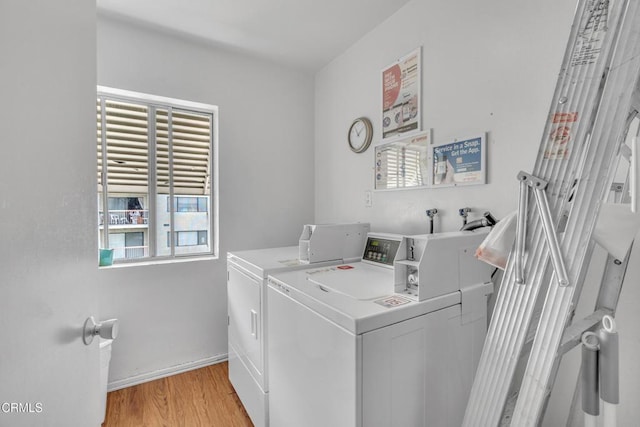 laundry room with baseboards, washer and clothes dryer, and light wood-style floors