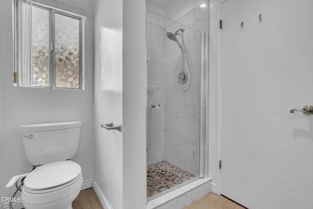 bathroom with toilet, baseboards, a shower stall, and tile patterned flooring
