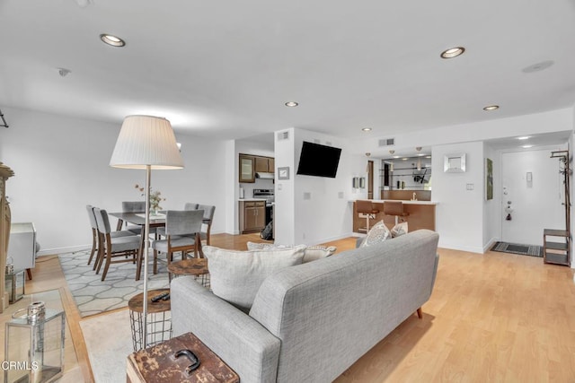 living room with light wood-style floors, recessed lighting, and baseboards
