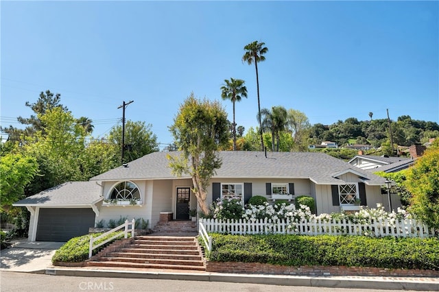 ranch-style house with fence private yard, an attached garage, roof with shingles, and concrete driveway