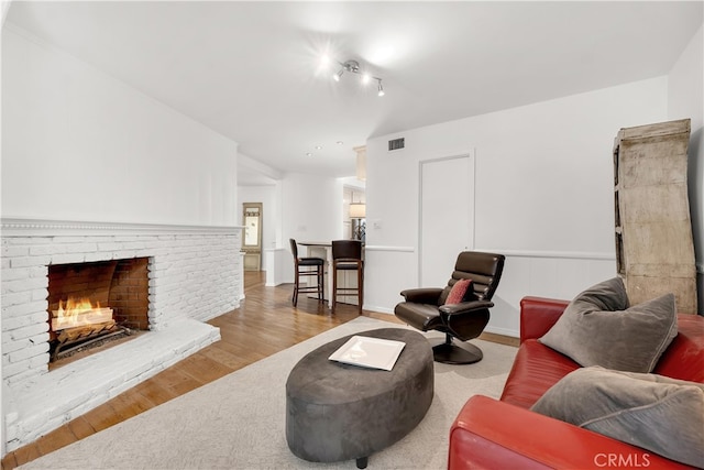 living area featuring visible vents, wood finished floors, and a fireplace