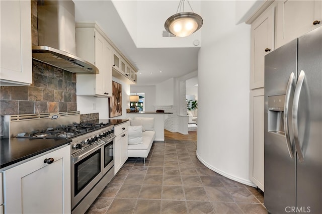 kitchen with stainless steel appliances, dark countertops, decorative backsplash, and wall chimney exhaust hood