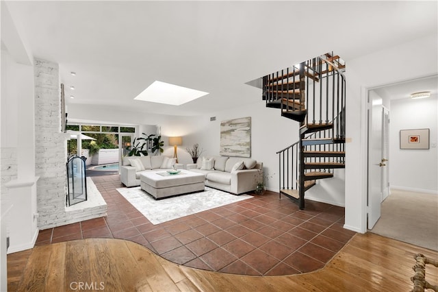 living area featuring baseboards, dark tile patterned flooring, a skylight, and stairway