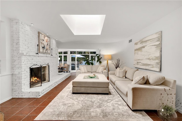 living area featuring dark tile patterned flooring, a skylight, visible vents, and a brick fireplace