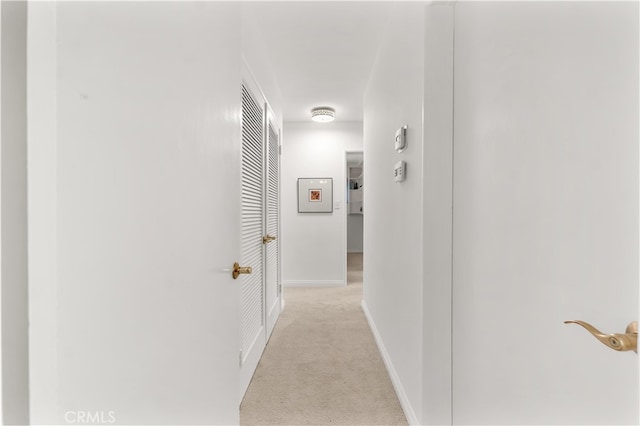 hallway with light colored carpet and baseboards