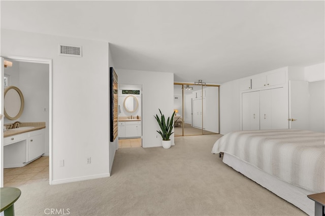 bedroom with visible vents, a sink, two closets, and light carpet