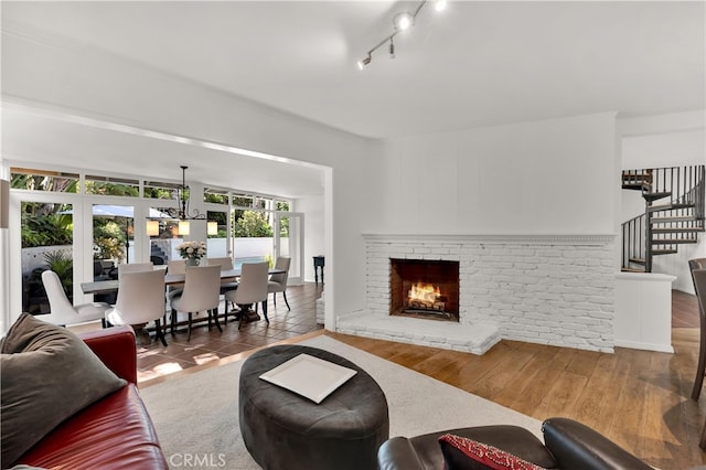 living room with rail lighting, stairs, and a brick fireplace