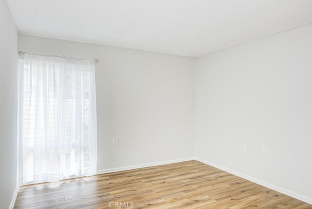 unfurnished room featuring baseboards and light wood finished floors