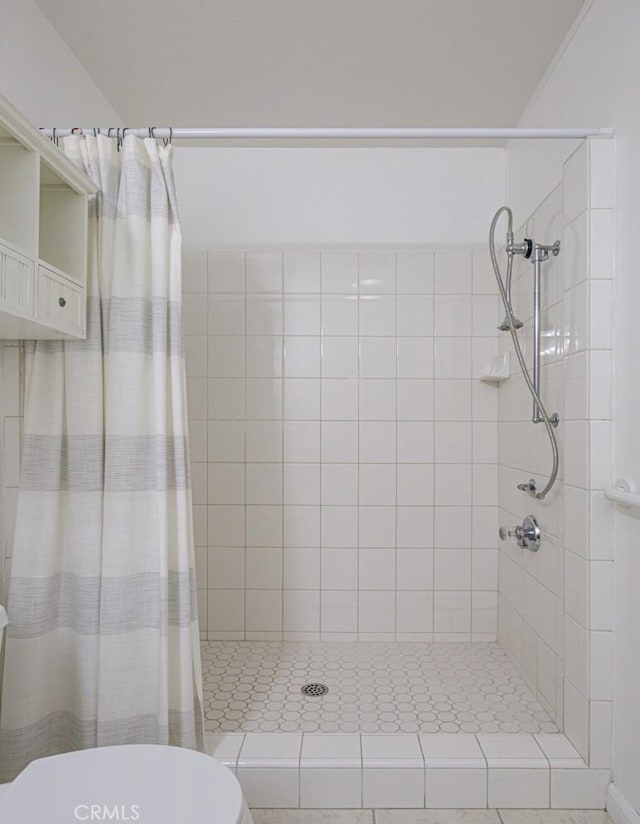 bathroom with tile patterned flooring, a tile shower, and toilet