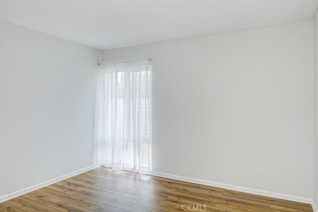 unfurnished room with baseboards and wood finished floors