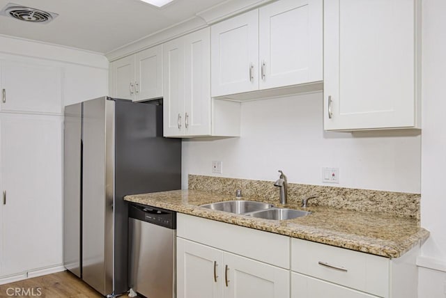 kitchen featuring visible vents, white cabinetry, light stone counters, a sink, and appliances with stainless steel finishes