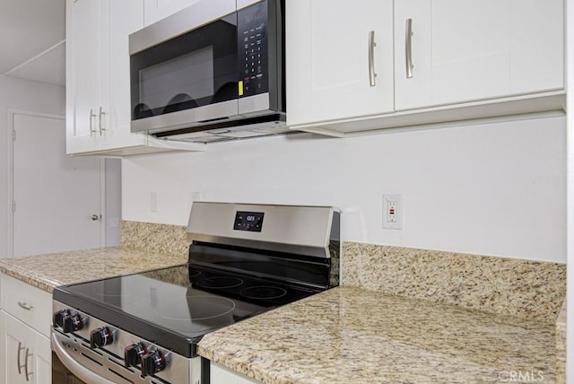 kitchen with light stone counters, white cabinets, and stainless steel appliances