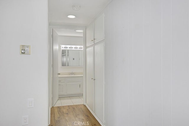 hallway featuring light wood-type flooring and a sink