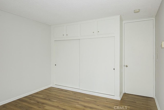 unfurnished bedroom with baseboards, a closet, and wood finished floors