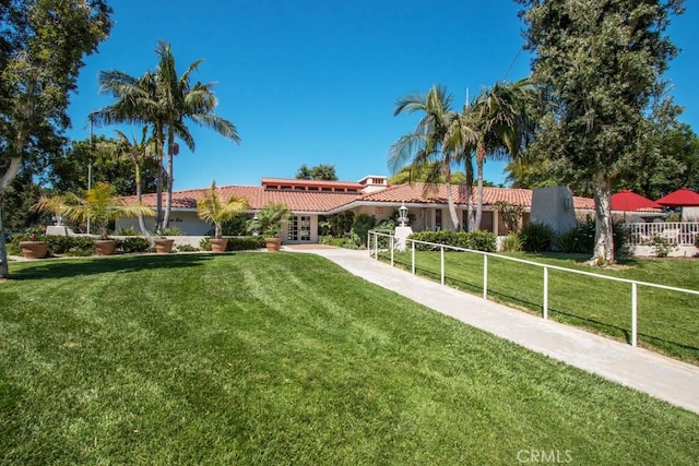 view of front of home with fence, stucco siding, a front yard, french doors, and a tiled roof