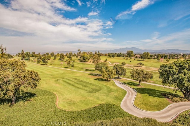 view of property's community featuring view of golf course, a mountain view, and a yard