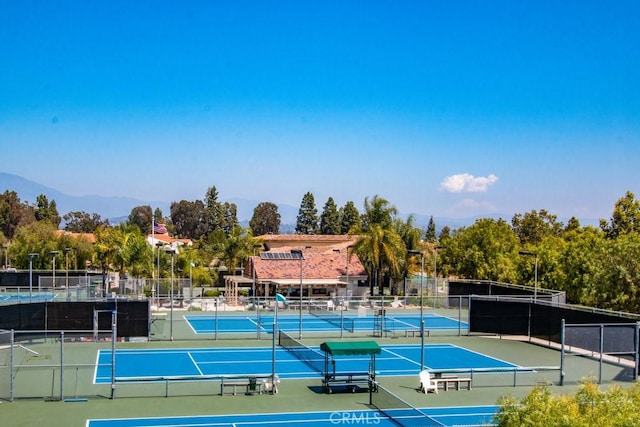 view of tennis court featuring fence and a mountain view