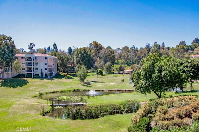 view of property's community featuring a lawn, a water view, and view of golf course