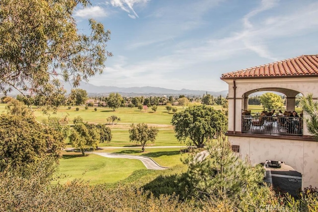 surrounding community with view of golf course, a mountain view, and a yard