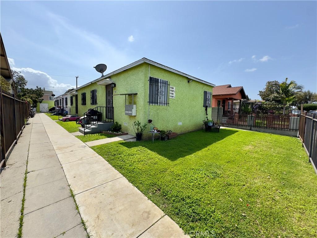 1104 W 87th St, Los Angeles, CA 90044 - view of home's exterior featuring stucco siding, a yard, and fence