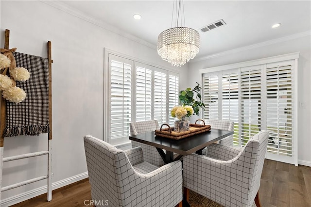 dining space with visible vents, crown molding, wood finished floors, baseboards, and a chandelier