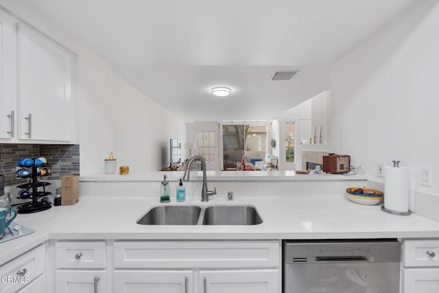 kitchen with visible vents, dishwasher, white cabinets, a sink, and backsplash