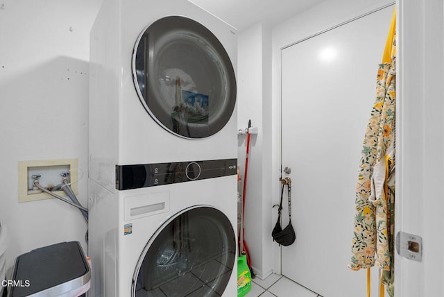 washroom with stacked washer and dryer, laundry area, and tile patterned flooring