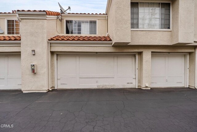 view of front of house featuring a garage, stucco siding, and a tile roof