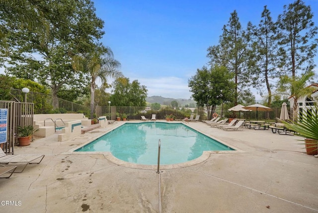 pool with fence, a mountain view, and a patio area