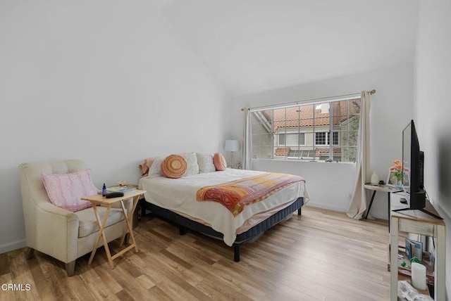 bedroom with baseboards, wood finished floors, and lofted ceiling