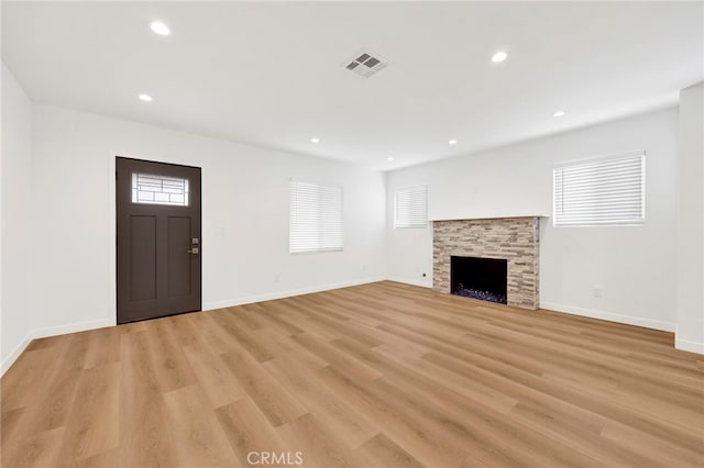 unfurnished living room with light wood-style floors, a stone fireplace, recessed lighting, baseboards, and visible vents