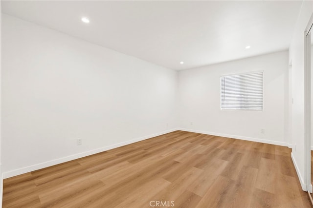 empty room featuring light wood-style floors, baseboards, and recessed lighting