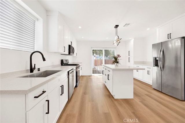 kitchen featuring visible vents, a kitchen island, recessed lighting, a sink, and appliances with stainless steel finishes