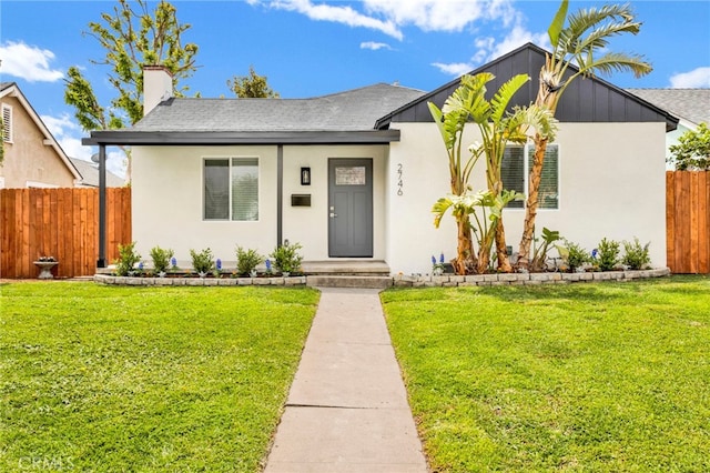view of front of home with fence, stucco siding, and a front yard