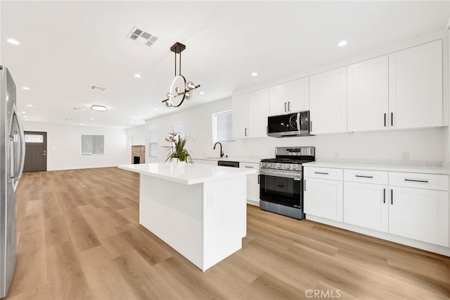 kitchen with visible vents, light wood-type flooring, light countertops, white cabinets, and appliances with stainless steel finishes