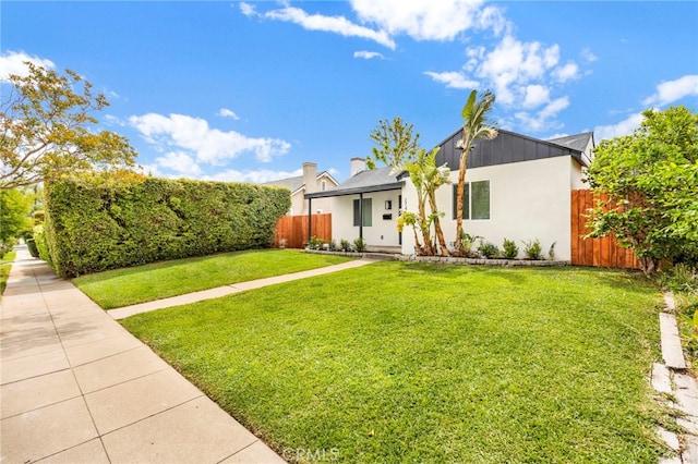 view of front of property featuring stucco siding, a front lawn, and fence