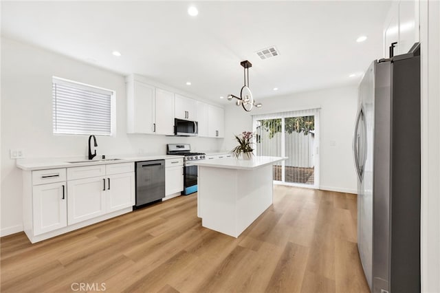 kitchen with visible vents, a sink, white cabinets, light wood-style floors, and stainless steel appliances