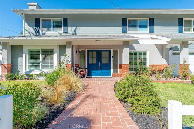 23341 Bessemer St, Woodland Hills, CA 91367 - view of exterior entry featuring brick siding, stucco siding, a chimney, and a porch