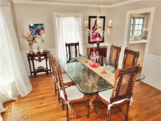 dining room with crown molding, plenty of natural light, wood finished floors, and a chandelier