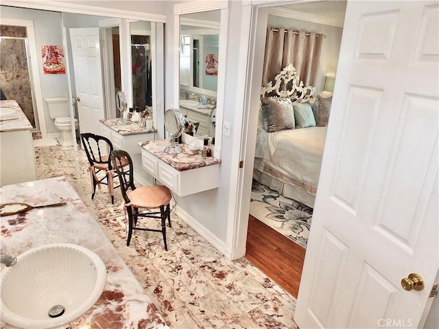full bath featuring vanity, wood finished floors, toilet, baseboards, and ensuite bathroom
