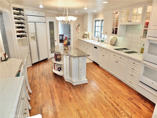 kitchen featuring crown molding, white cabinets, paneled appliances, and a notable chandelier