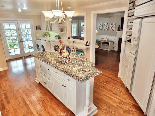 kitchen featuring crown molding, a center island, white microwave, and a notable chandelier