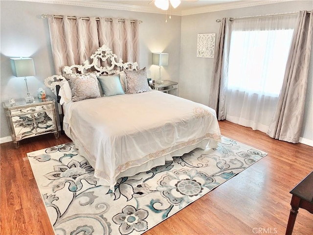 bedroom with baseboards, ornamental molding, and wood finished floors