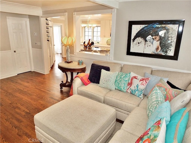 living room with an inviting chandelier, ornamental molding, and wood finished floors