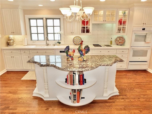 kitchen with a kitchen island, double oven, an inviting chandelier, a warming drawer, and white cabinetry