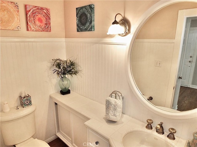 bathroom with vanity, wainscoting, and toilet