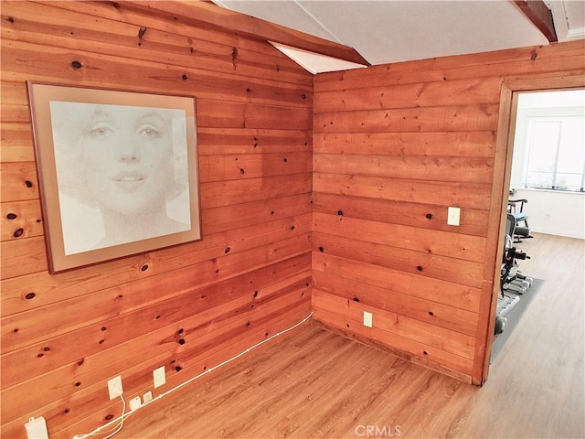 unfurnished room with wood walls and light wood finished floors
