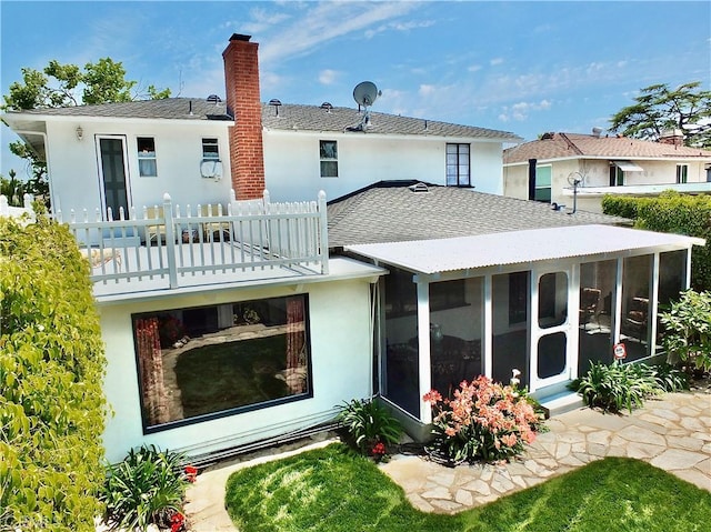 back of property featuring a sunroom, stucco siding, and a chimney