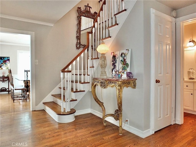 staircase with crown molding, baseboards, and wood finished floors
