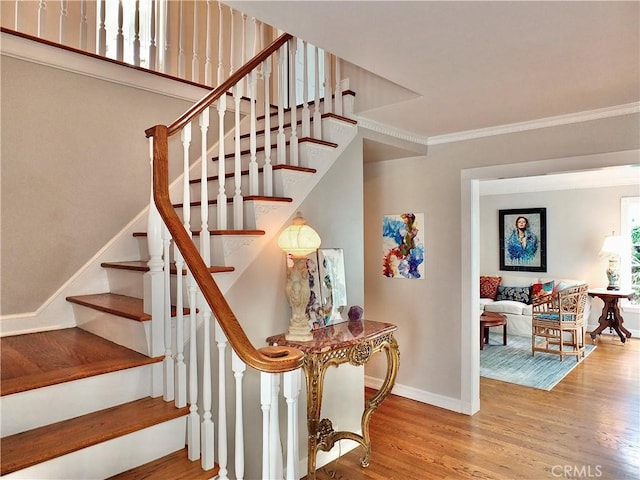 stairs with crown molding, baseboards, and wood finished floors